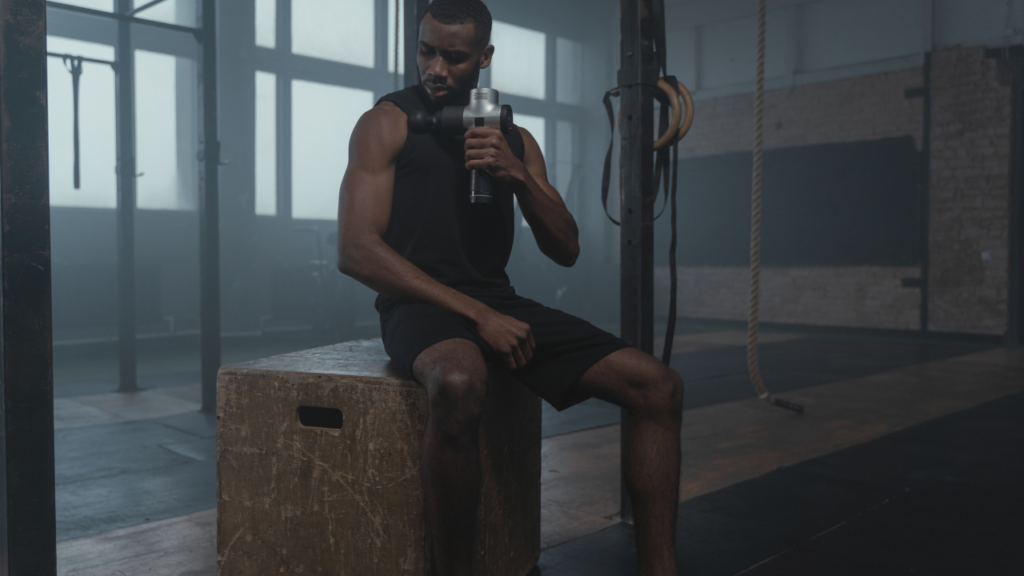 man using a massage gun for muscle knots